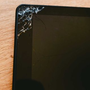 The top left corner of a tablet or ipad screen is severely cracked, with multiple fractures spreading across the glass.